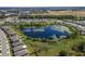 Aerial view of houses bordering a lush community pond and grassy common area surrounded by a well-maintained neighborhood at 17394 Million Lakes Ct, Clermont, FL 34714