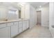 Bright bathroom featuring double sinks, granite countertops, a large mirror, and tiled floors at 17394 Million Lakes Ct, Clermont, FL 34714