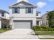 Charming two-story home featuring light gray siding, blue shutters, a two-car garage, and well-maintained landscaping at 17394 Million Lakes Ct, Clermont, FL 34714