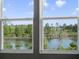 Beautiful lake view from a window, framed by lush trees and blue skies at 17394 Million Lakes Ct, Clermont, FL 34714