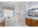 Stylish bathroom with a soaking tub, glass block window, tiled shower, and wooden vanity at 2106 Ridgewind Way, Windermere, FL 34786