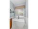 Close-up of a modern soaking tub with marble-like tile and a large glass block window at 2106 Ridgewind Way, Windermere, FL 34786