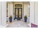 Close-up of the front door entrance featuring glass inserts and potted plants on a tiled porch at 2106 Ridgewind Way, Windermere, FL 34786