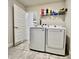 Bright laundry room with tile floors, washer, dryer and storage shelf at 2107 Cartgate Ln, Winter Haven, FL 33884