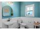 Stylish bathroom with a pedestal sink, a round mirror, and bright teal walls at 2108 Delaney Ave, Orlando, FL 32806