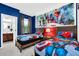 This bedroom features two beds with superhero themed decor, and a bright blue wall with a custom mural at 2557 Shanti Dr, Kissimmee, FL 34746