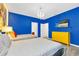 Brightly colored bedroom with vibrant blue walls, two beds, and 