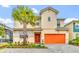 Inviting two-story home featuring a vibrant orange garage door and a lush palm tree in the front yard at 2557 Shanti Dr, Kissimmee, FL 34746