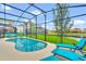 A screened-in pool area features lounge chairs, a well-manicured lawn, and a scenic lake view at 2557 Shanti Dr, Kissimmee, FL 34746