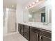 Bathroom featuring double sinks, a large mirror, wood cabinets, and a glass-enclosed shower at 325 St Georges Cir, Eagle Lake, FL 33839