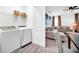 A modern laundry room featuring a white washer and dryer with overhead shelving and accent containers at 4405 Durga Ln, Kissimmee, FL 34746