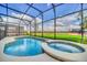 Screened-in pool and spa area with clear blue water, surrounded by lush greenery and views of the surrounding landscape at 4405 Durga Ln, Kissimmee, FL 34746