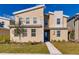 Modern two-story home with tan siding and stone accents, complemented by a well-manicured lawn and inviting landscaping at 2859 Bookmark Dr, Kissimmee, FL 34746