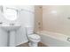 Bathroom with pedestal sink, modern toilet, bathtub, chrome fixtures, and tile surround at 4770 Cypress Forest Ln, St Cloud, FL 34772