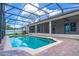 Sparkling screened-in pool featuring a brick paver deck and a serene view of the surrounding greenery at 4770 Cypress Forest Ln, St Cloud, FL 34772