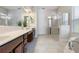 Bright bathroom featuring double vanities, a glass-enclosed shower, a soaking tub, and tile flooring at 6155 Hedgesparrows Ln, Sanford, FL 32771