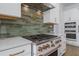 Kitchen details featuring a stainless steel range, pot filler, white cabinets, and earth-toned backsplash tiles at 640 Old Horatio Ave, Maitland, FL 32751