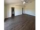 Neutral main bedroom with wood-look floors, a ceiling fan, and doorways to the bathroom and walk-in closet at 7847 Golf Paradise Way, Clermont, FL 34711