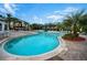 Community pool featuring clear water, lounge chairs, umbrellas, and beautiful landscaping at 8819 Dunes Ct # 208, Kissimmee, FL 34747