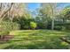 Expansive backyard showcases a lush lawn surrounded by mature trees and landscaping at 9783 Covent Garden Dr, Orlando, FL 32827