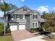 Two-story home with brick driveway, three-car garage, well-manicured landscaping, and gray exterior at 10303 Atwater Bay Dr, Winter Garden, FL 34787