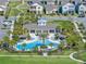 Aerial view of a community pool featuring a splash pad, covered seating, lounge chairs, palm trees and lush landscaping at 10303 Atwater Bay Dr, Winter Garden, FL 34787