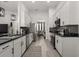 Galley kitchen featuring white cabinets, black countertops, stainless steel appliances, and modern lighting at 1113 Caloosa Ridge Way, Babson Park, FL 33827