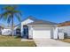 Charming single-story home with a well-manicured lawn, mature palm tree, and attached two-car garage in a serene neighborhood at 121 Sonja Cir, Davenport, FL 33897