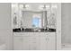 Bright bathroom with double sinks, black countertop, white cabinetry, and a large mirror at 150 E Robinson St # 2608, Orlando, FL 32801