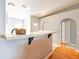 Kitchen bar area with hardwood floors, an arched doorway, and a view of the kitchen with white cabinets at 15733 Switch Cane St, Clermont, FL 34711