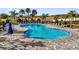 Kidney-shaped community pool with plenty of lounge chairs and umbrellas for relaxation at 3029 High Pointe St, Clermont, FL 34711