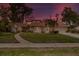 Charming single-story home featuring stone accents, a well-maintained lawn, and mature trees under a colorful twilight sky at 320 Isabella Dr, Longwood, FL 32750
