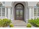 Elegant double front doors with decorative glass and sidelights, framed by white columns and manicured landscaping at 3340 Fernlake Pl, Longwood, FL 32779
