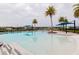 Large community pool surrounded by palm trees, blue umbrellas, and comfortable lounge chairs at 345 Aquamarine Way, Daytona Beach, FL 32124