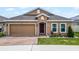 Tan single-story home with a red-brick driveway, tidy landscaping, and an attached two-car garage at 434 Ironside Trail Dr, Groveland, FL 34736