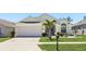 Charming single-story home with a well-manicured lawn, palm tree, and attached two-car garage at 442 Troon Cir, Davenport, FL 33897