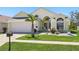 Charming, single story, yellow home with a manicured front lawn, palm tree, and two-car garage at 442 Troon Cir, Davenport, FL 33897