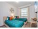 Cozy bedroom featuring two twin beds with teal bedspreads, an accent mirror, and a window at 4751 Clock Tower Dr # 203, Kissimmee, FL 34746