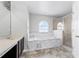 Bright bathroom featuring a garden tub with marble surround and a separate glass-enclosed shower at 5456 Crepe Myrtle Cir, Kissimmee, FL 34758