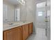 Well-lit bathroom featuring double sinks and a doorway leading to a bathtub and shower at 5456 Crepe Myrtle Cir, Kissimmee, FL 34758
