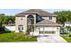 Beige two story home with a front yard, two-car garage, and arched windows at 5456 Crepe Myrtle Cir, Kissimmee, FL 34758
