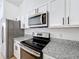 Well-equipped kitchen featuring stainless steel appliances, granite countertops, and white cabinets offers modern convenience at 6921 Blair Dr, Orlando, FL 32818