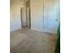 A bright, carpeted bedroom features neutral walls, a door, and an open doorway at 992 Serchio St, Haines City, FL 33844