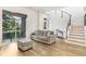 Cozy living room featuring modern staircase, sliding door, and a comfortable gray sofa at 10372 Austrina Oak Loop, Winter Garden, FL 34787