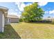 Large backyard featuring lush green grass, a mature tree, and a wood fence at 1456 Providence Blvd, Deltona, FL 32725