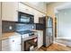 Bright kitchen showcasing stainless steel appliances, white cabinetry, and a black subway tile backsplash at 1456 Providence Blvd, Deltona, FL 32725