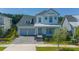 Exterior view of the home with a gray roof, a driveway, landscaping, and a mix of light colors at 14691 Walcott Ave, Orlando, FL 32827