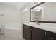 Well-lit bathroom showcasing a soaking tub, vanity with dark wood cabinets, and a large mirror at 1740 Efland Ter, Deltona, FL 32738