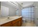 Well-lit bathroom with wood vanity, large mirror, shower with striped curtain, and tile floor at 2204 Hammock Moss Dr, Orlando, FL 32820