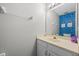 A half bathroom with a cream color vanity, mirror and bright blue wallpaper featuring circular patterns at 2204 Hammock Moss Dr, Orlando, FL 32820